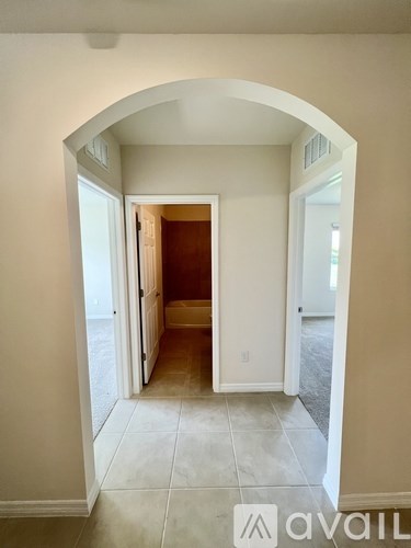 A hallway with a white arched doorway leading to a bedroom.