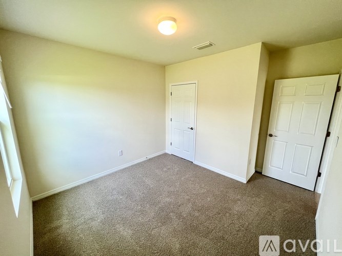 A room with a carpeted floor and two doors.