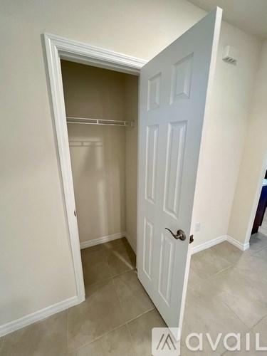 A white door is open to a small empty room.
