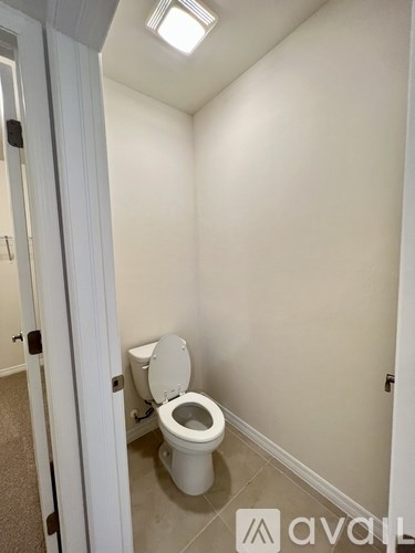 A white toilet in a small bathroom with a carpeted floor.
