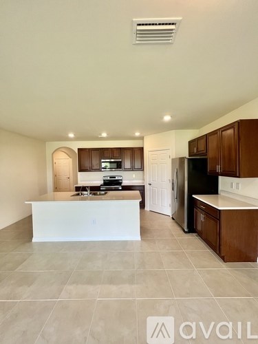 A modern kitchen with a white island and dark wood cabinets.
