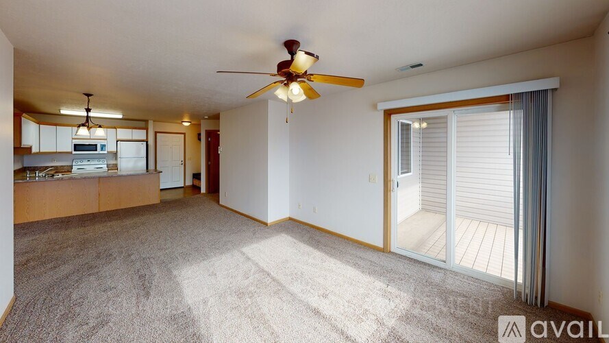 A spacious living room with a ceiling fan and sliding glass doors.