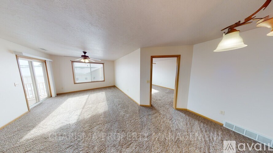 A spacious room with a carpeted floor and a ceiling fan.