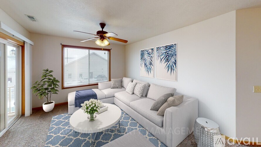 A living room with a white couch, a ceiling fan, and a plant.