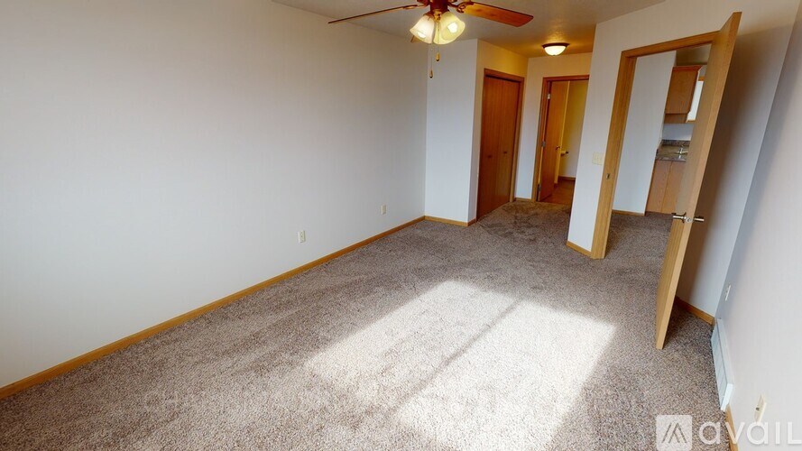 A room with a carpeted floor and a ceiling fan.