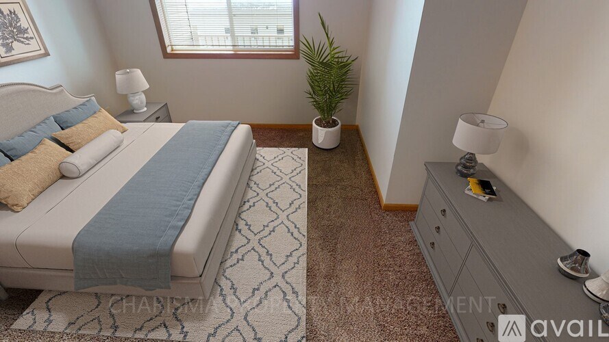 A bedroom with a bed, nightstand, and a plant.