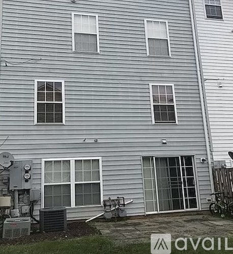 A grey house with a satellite dish and a window air conditioner.