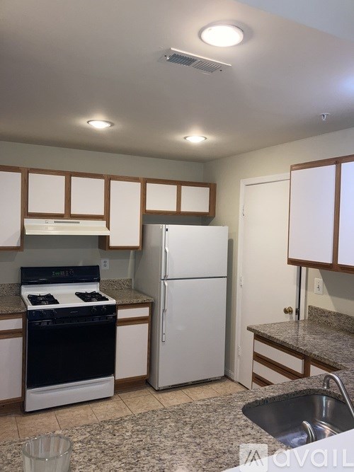 A kitchen with a black stove top oven and a white refrigerator.