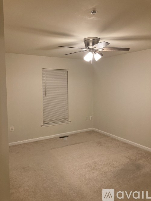 A room with a ceiling fan and a window with blinds.