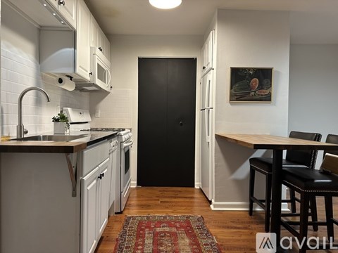 A kitchen with white cabinets and a black door.