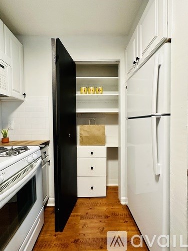 A kitchen with a black refrigerator and white cabinets.