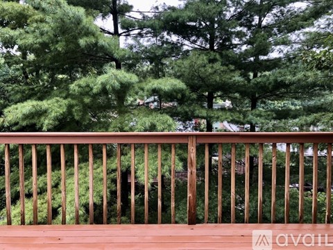 A wooden deck with a railing overlooking a forest of trees.
