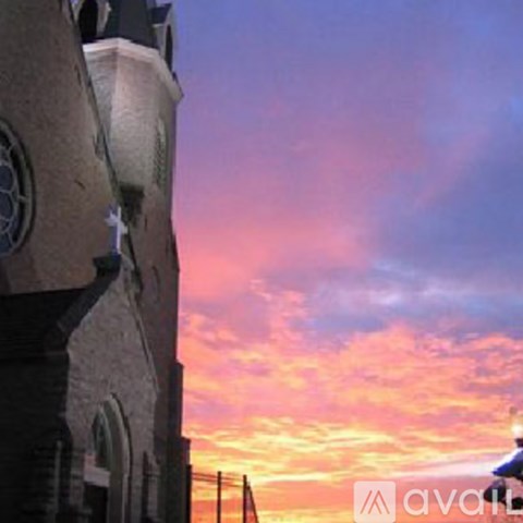A building with a clock tower is silhouetted against a sunset sky.
