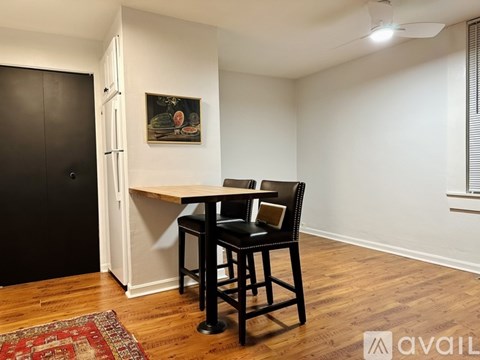 A room with a black chair and a small table with a painting on the wall.