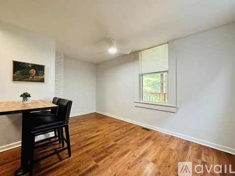 A room with a wooden floor, a table with two chairs, and a painting on the wall.