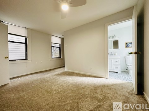 A room with beige carpet and two windows.