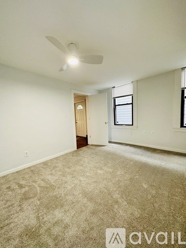 A room with a carpeted floor and a ceiling fan.