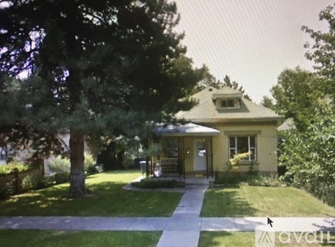 A house with a yellow front and a tree in front of it.