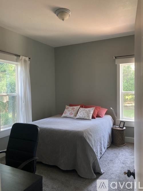 A bedroom with a bed, chair, and window.