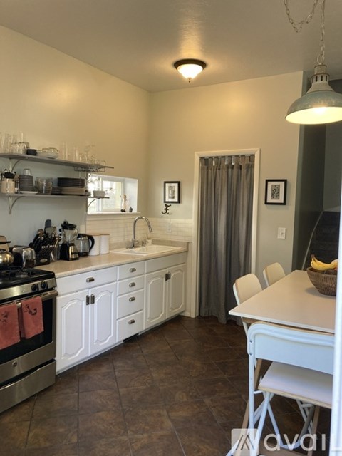 A kitchen with white cabinets and a stove top oven.