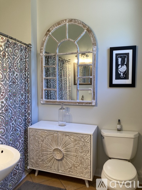 A bathroom with a white toilet, a sink, a mirror, and a cabinet.