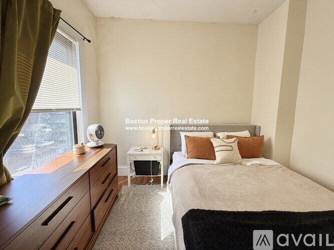 A bedroom with a bed, nightstand, and window.