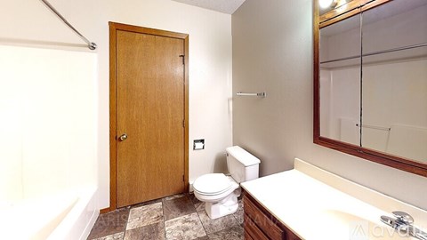 A bathroom with a toilet, sink, and mirror.