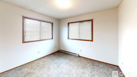 A room with two windows and carpeted floor.