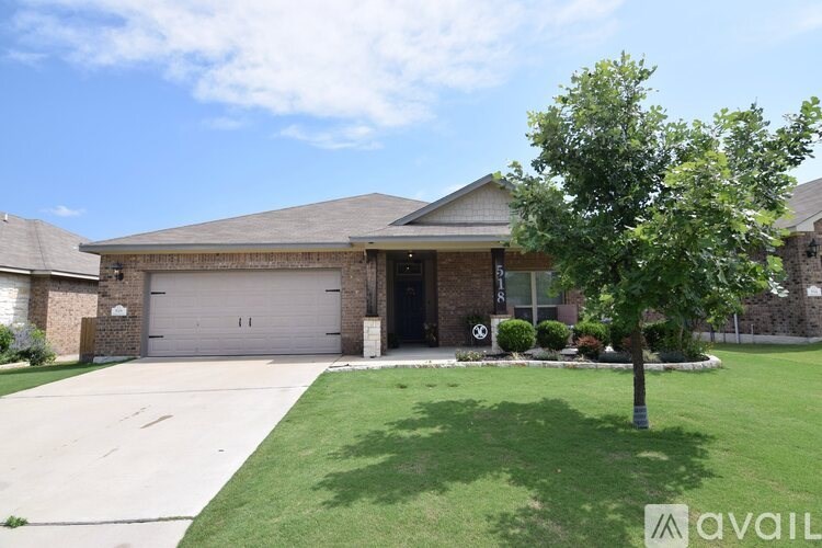 A house with a garage and a tree in front.