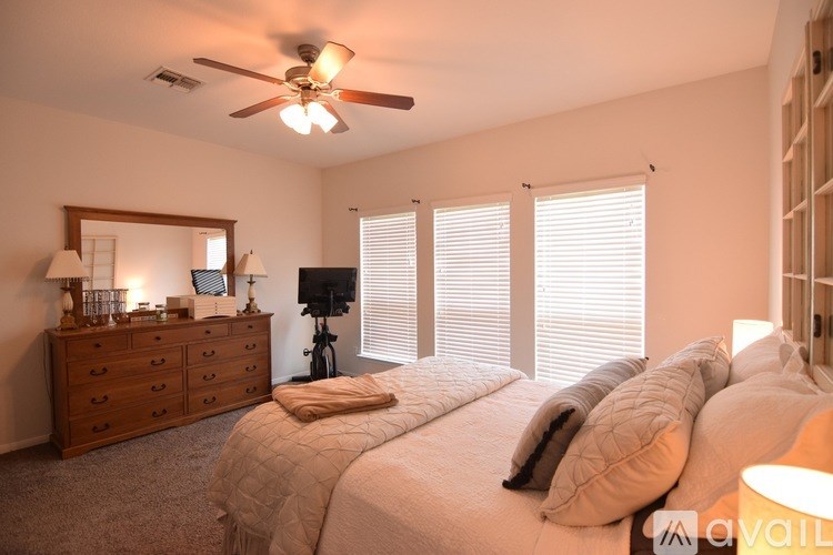 A bedroom with a large bed, a dresser, and a ceiling fan.