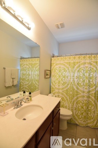 A bathroom with a green and white shower curtain.
