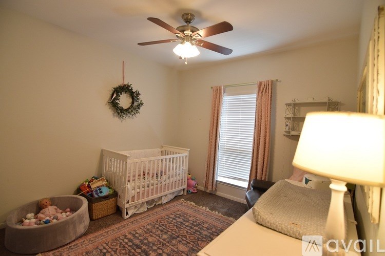 A baby room with a crib, a wreath, a rocking chair and a lamp.