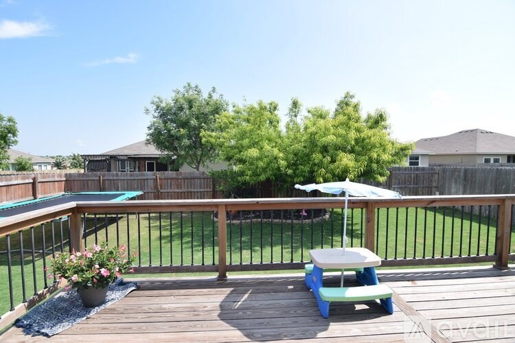 A wooden deck with a table and chairs and a pool in the background.