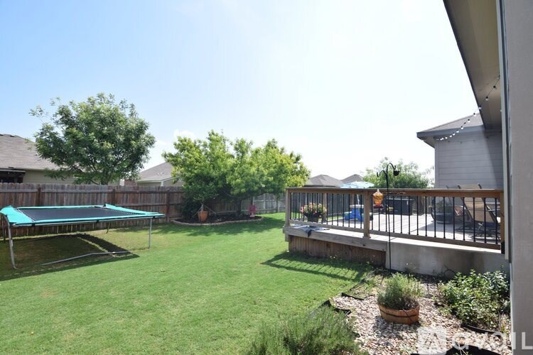 A backyard with a trampoline and a deck.
