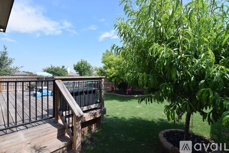 A deck with a railing and a tree in a pot.