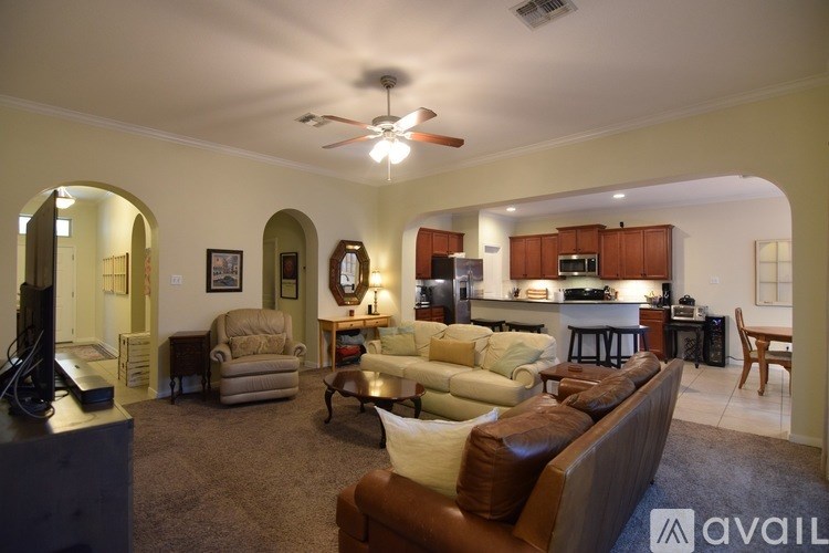 A living room with a brown couch and a ceiling fan.