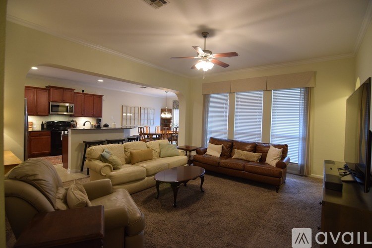 A living room with a brown couch and a ceiling fan.