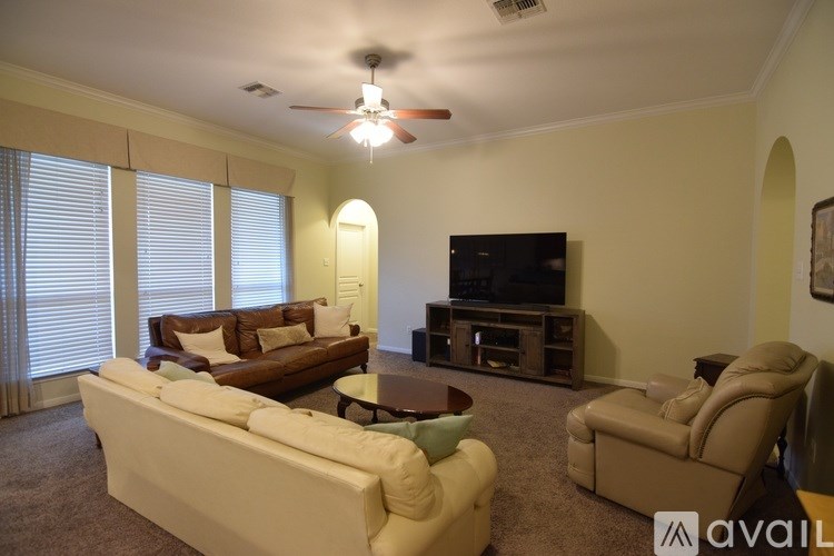 A living room with a white couch, a brown couch, a coffee table, and a television.
