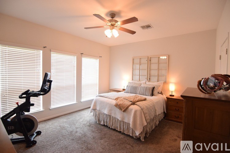 A bedroom with a bed, a chair, and a ceiling fan.