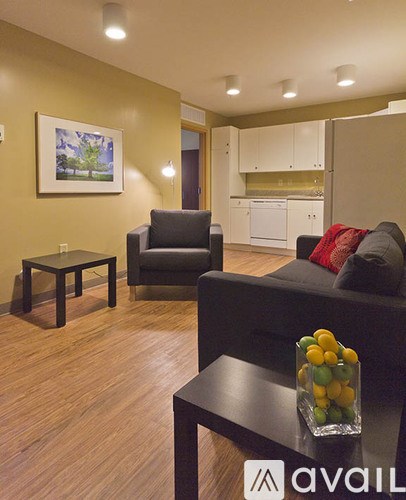 A living room with a black couch and a glass of fruit on the coffee table.