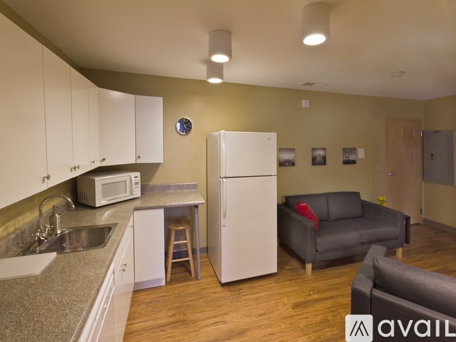 A kitchen with a white refrigerator and a grey couch.