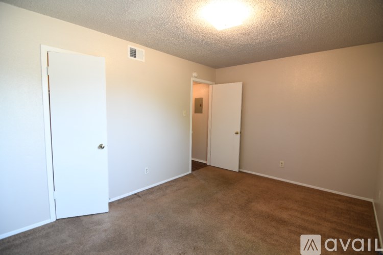 A room with a carpeted floor and two doors.