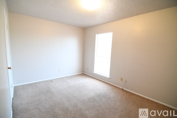A room with a carpeted floor and a window letting in sunlight.