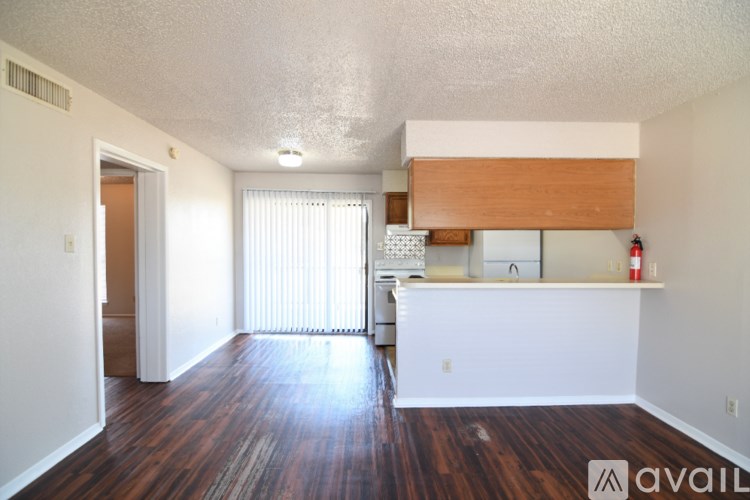 A room with wooden floors and white walls, with a window covered by white blinds.