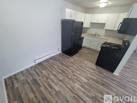 A kitchen with black appliances and wooden flooring.