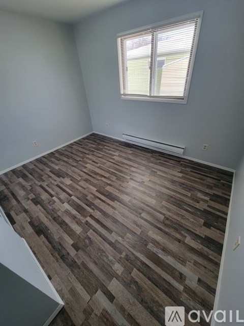 A room with wooden flooring and a window.