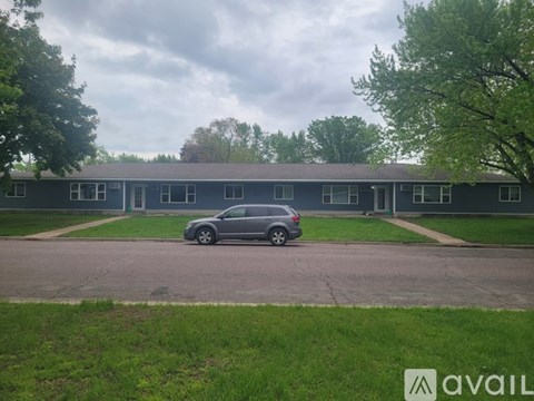A grey car is parked in front of a grey building.