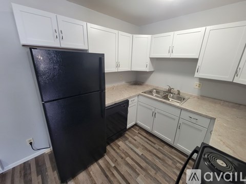 A kitchen with a black fridge and white cabinets.