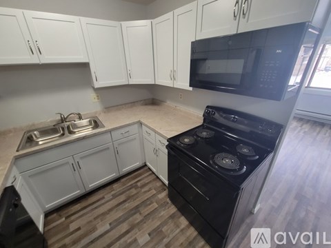 A kitchen with white cabinets and a black stove top oven.