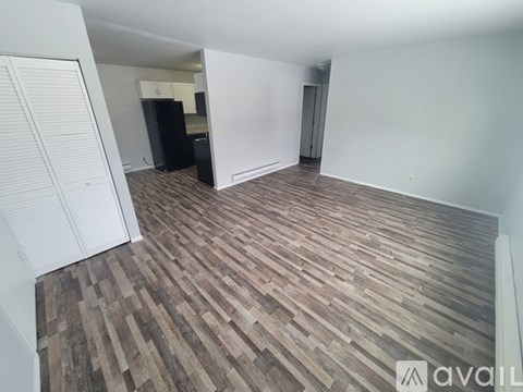 A room with wooden flooring and a white wall with a door.